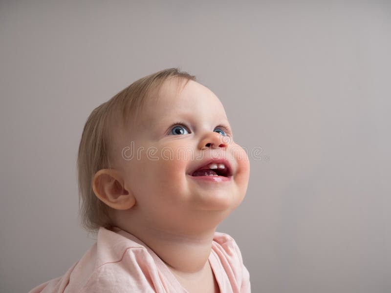 Portrait of a happy laughing baby, with a funny expression on his face. A small beautiful girl with blue eyes smiles cheerfully