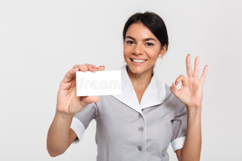 Portrait of happy maid in uniform showing empty sign card and OK royalty free stock image