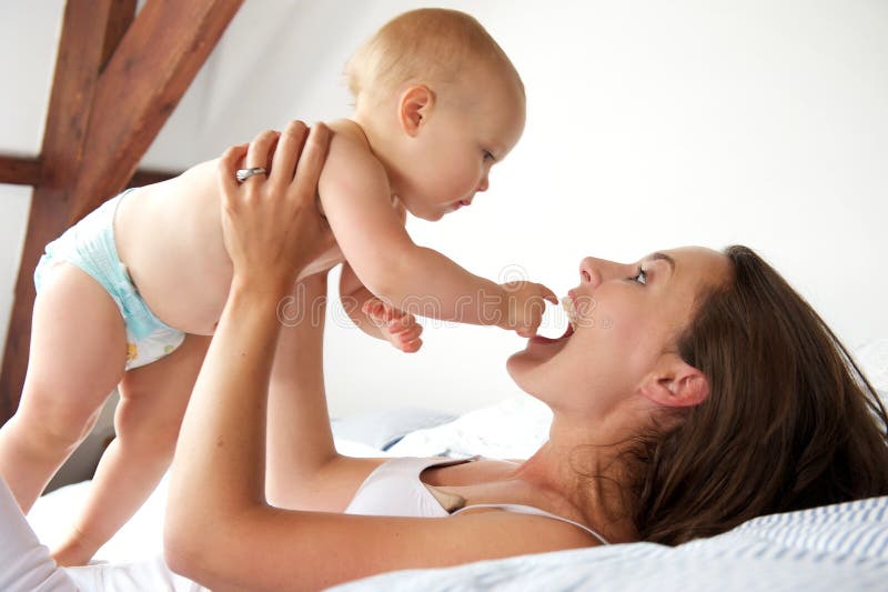 Portrait of a happy mother and baby playing in bed