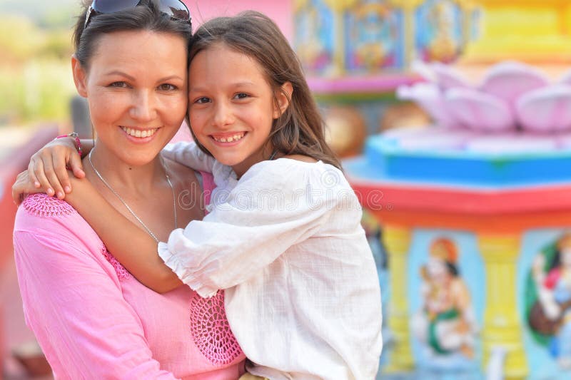 Happy mother and daughter posing on blurred amusement park background. Happy mother and daughter posing on blurred amusement park background