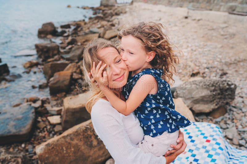 Portrait of happy mother and daughter spending time together on the beach on summer vacation. Happy family traveling, cozy mood.