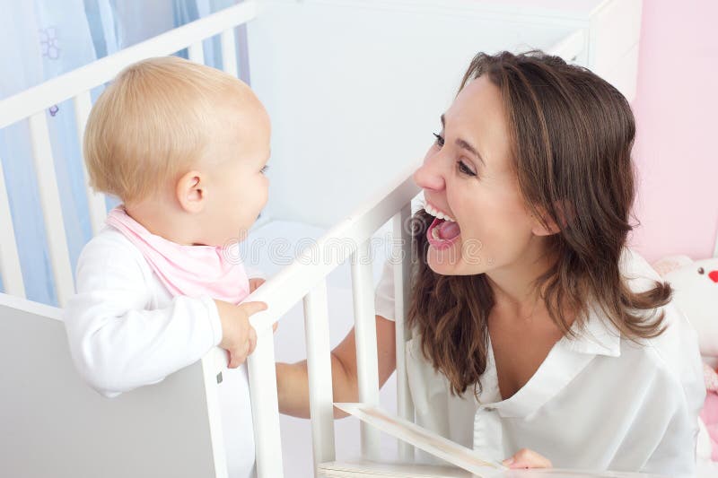 Portrait of a happy mother laughing with cute baby in crib stock image Portrait of a happy mother laughing with cute baby in crib stock image