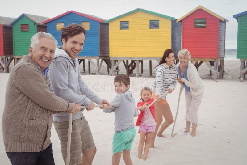 Portrait of happy multi-generation family playing tug of war at beach