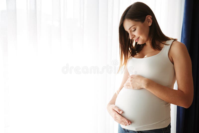 Portrait of a happy pregnant woman touching her belly stock photos Portrait of a happy pregnant woman touching her belly stock photos