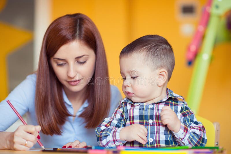 Portrait of happy pretty mother with her toddler son drawing