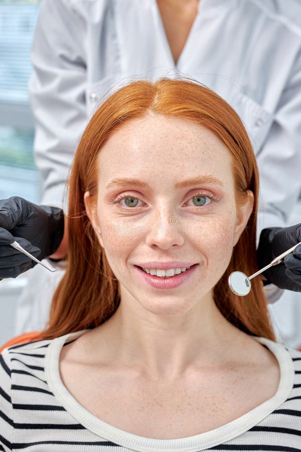 Portrait of Happy redhead woman is being examined by dentist at dental clinic.