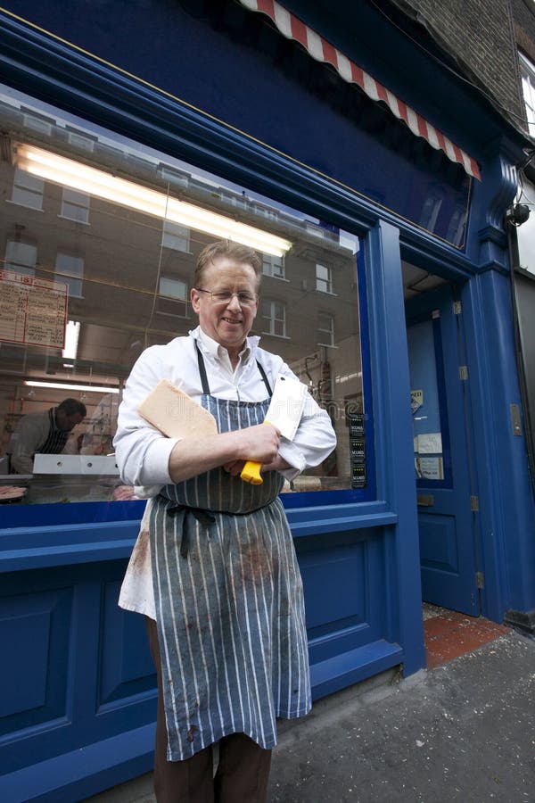 Portrait of a happy senior butcher standing outside shop with cleaver stock photo Portrait of a happy senior butcher standing outside shop with cleaver stock photo