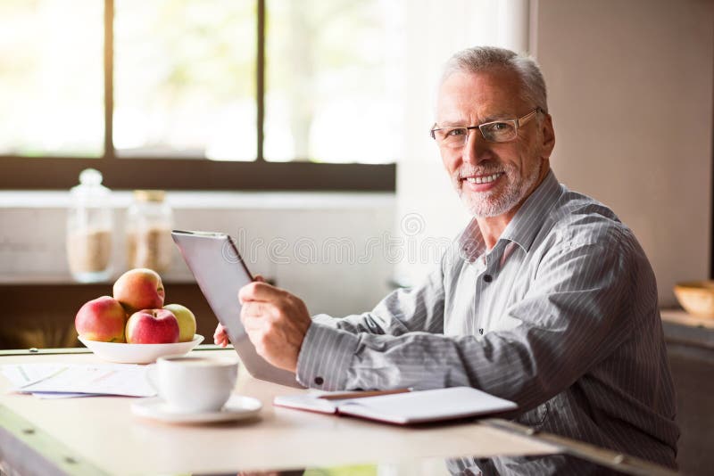Portrait of happy senior man using laptop in kitchen at home royalty free stock photos Portrait of happy senior man using laptop in kitchen at home royalty free stock photos