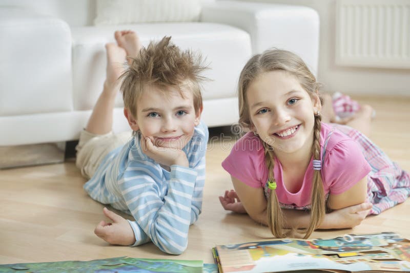 Portretul fraților fericiți cu cărți de povești pe podea în sufragerie stock photo