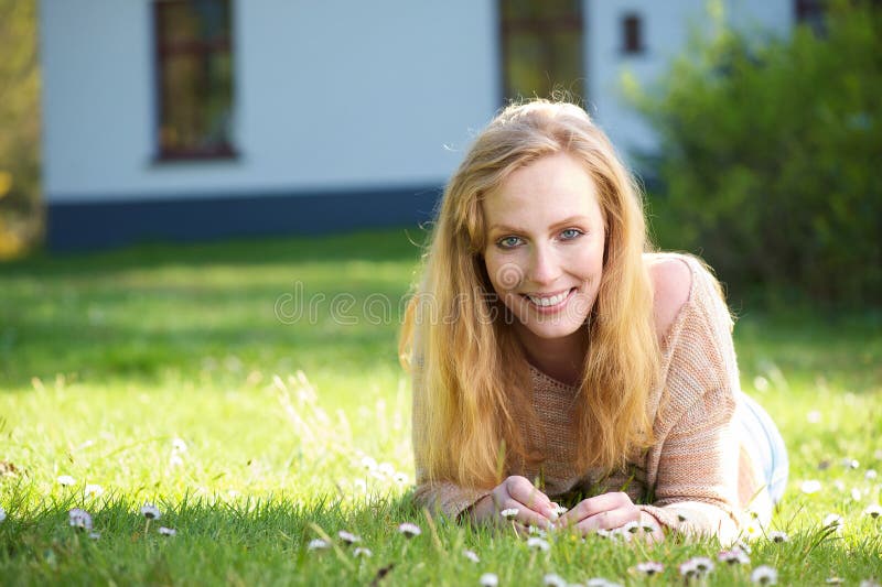 Portrait of a happy woman lying on grass outdoors