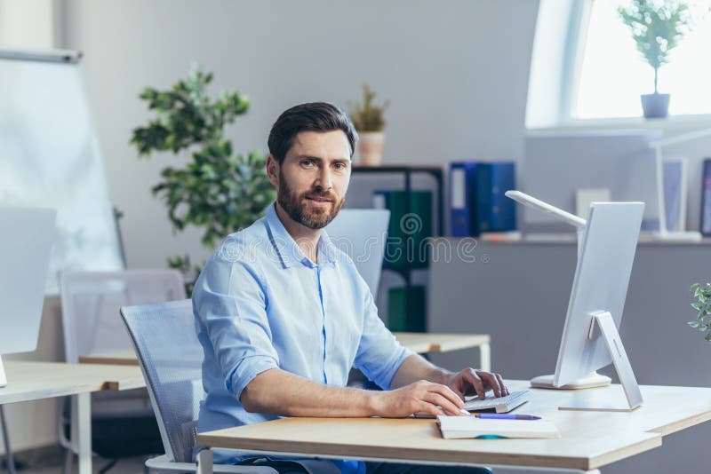 Portrait of happy worker, man working in modern bright office, looking at camera and smiling royalty free stock images