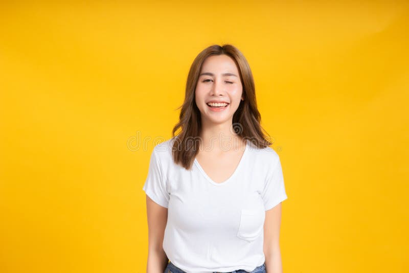 Portrait happy young asian woman laughing blink, wink eye joyful funny positive emotion in white t-shirt. Yellow background isolated studio shot and copy space royalty free stock photography Portrait happy young asian woman laughing blink, wink eye joyful funny positive emotion in white t-shirt. Yellow background isolated studio shot and copy space royalty free stock photography