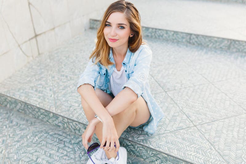 Portrait of a happy young Caucasian woman sitting on light gray steps smiling stock photos Portrait of a happy young Caucasian woman sitting on light gray steps smiling stock photos