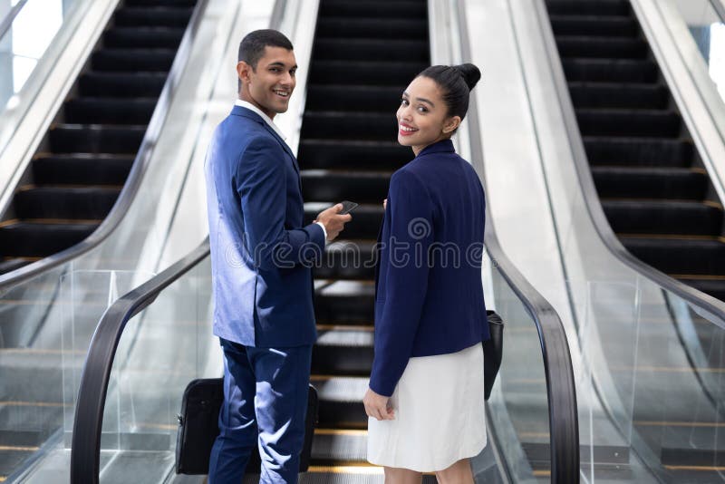 Young mixed-race business people looking at camera while using escalator in modern office royalty free stock photo Young mixed-race business people looking at camera while using escalator in modern office royalty free stock photo
