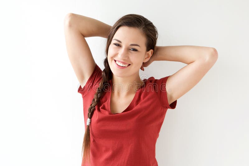 Happy young woman with hands behind head against white background. 