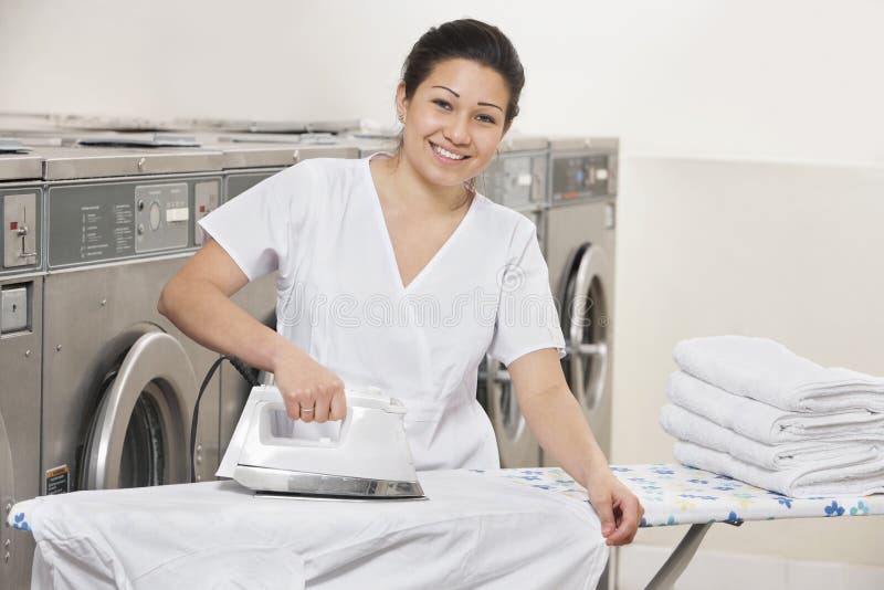 Portrait of a happy young woman ironing clothes in Laundromat royalty free stock photo Portrait of a happy young woman ironing clothes in Laundromat royalty free stock photo