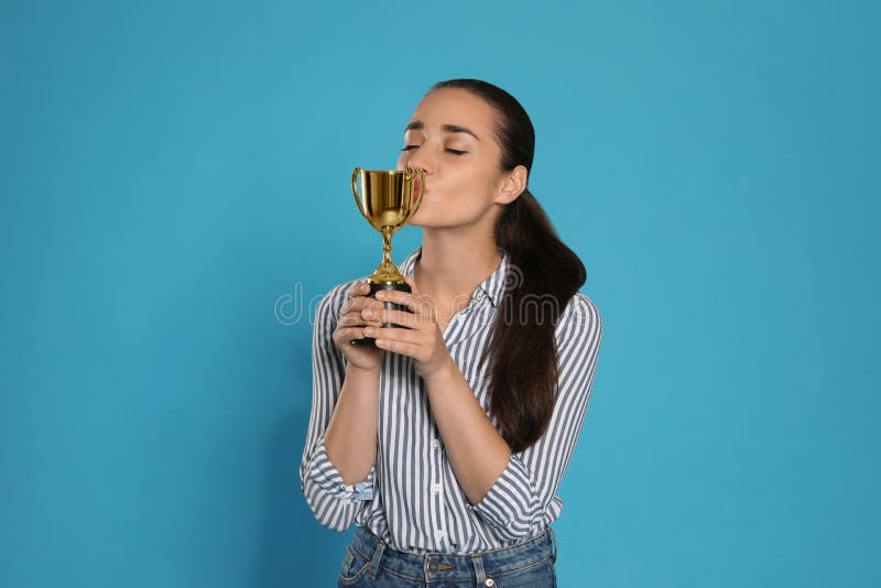 Portrait of happy young woman kissing gold trophy cup stock photo Portrait of happy young woman kissing gold trophy cup stock photo