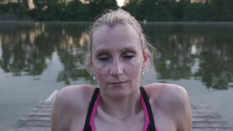 Portrait haut près d'une femme dans les vêtements de sport assis sur un pilier clips vidéos