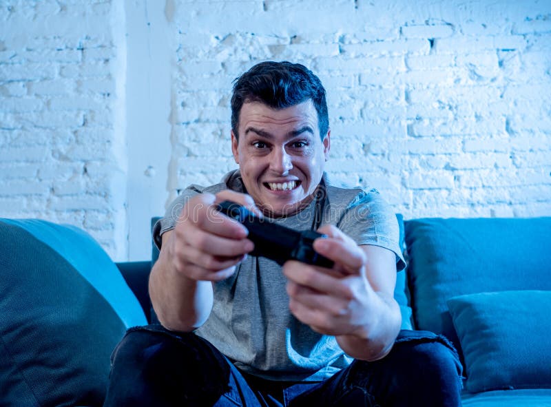 Portrait haut étroit de jeune homme jouant le jeu vidéo la nuit adonné à lui ayant l'amusement photo stock Portrait haut étroit de jeune homme jouant le jeu vidéo la nuit adonné à lui ayant l'amusement photo stock