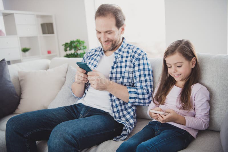 Sitting on divan using cell playing game in stock photos.