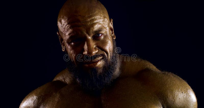 Portrait Of A Huge Bald Bearded Man With Bronze Skin On A Black