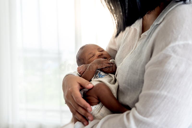 Portrait images of half African half Thai, 12-day-old baby newborn son, sleeping with his mother being held. To family and infant newborn concept