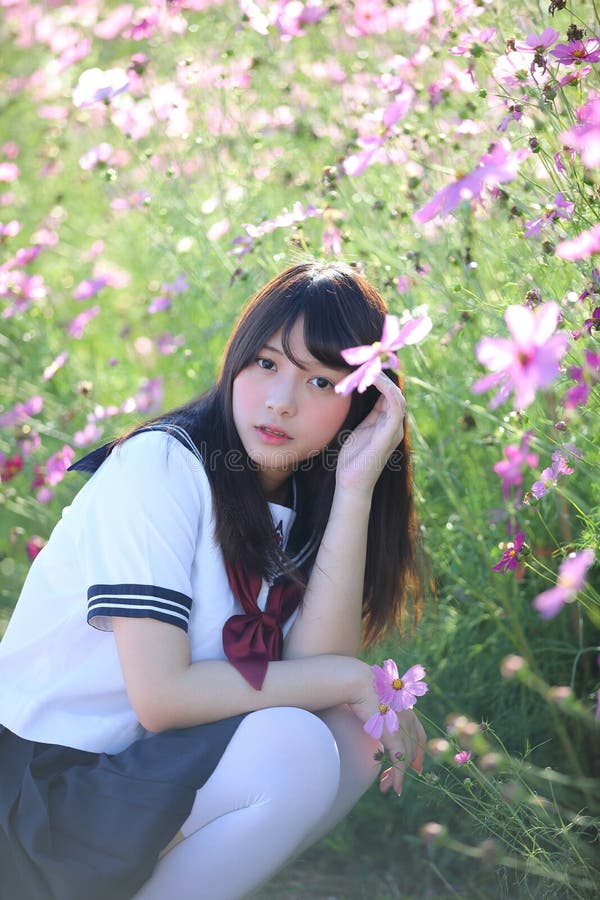 Portrait of Japanese school girl uniform sitting with cosmos flower.