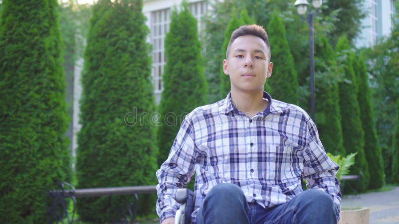 Portrait jeune asiatique handicapé en fauteuil roulant dans le parc banque de vidéos