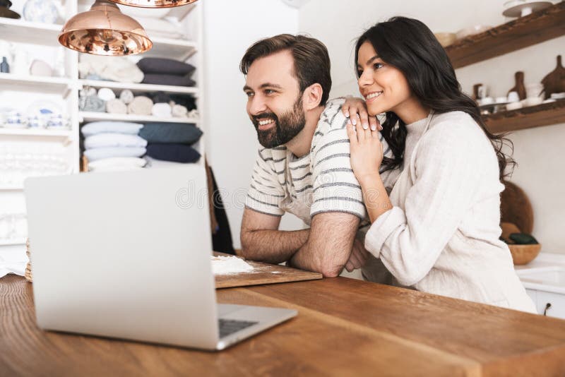 Portrait of joyful couple looking at laptop while cooking pastry in kitchen at home royalty free stock photos Portrait of joyful couple looking at laptop while cooking pastry in kitchen at home royalty free stock photos