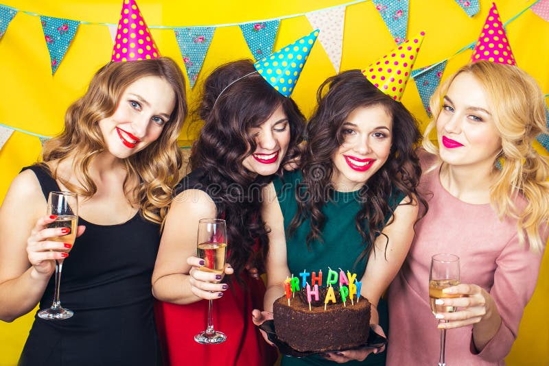 Portrait of joyful friends toasting and looking at camera at birthday party.Smiling girls with glasses of champagne