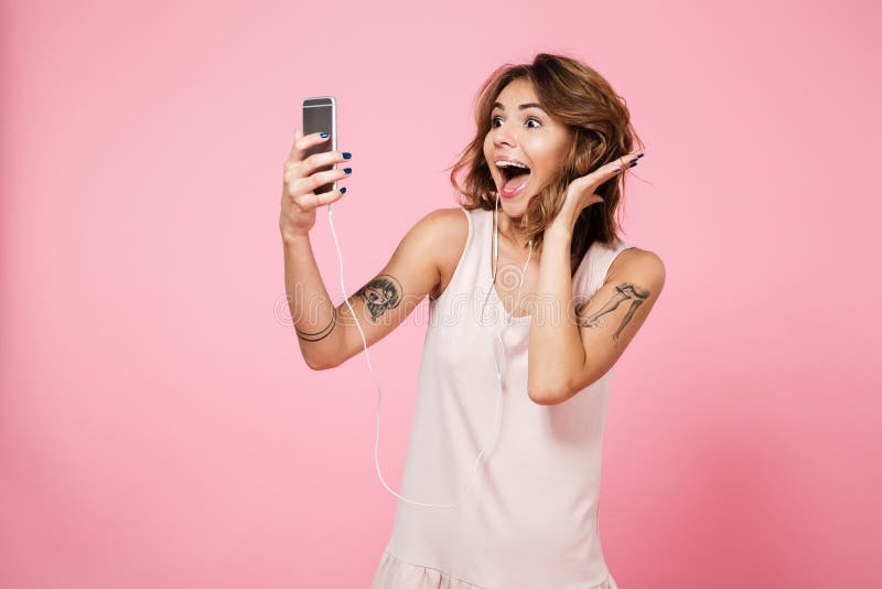 Portrait of a joyful pretty girl listening music with earphones