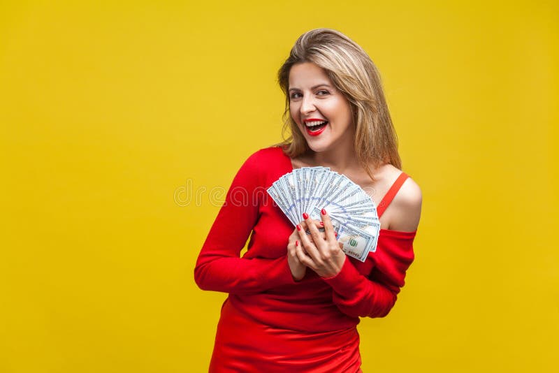 Portrait of joyous wealthy beautiful woman in red dress holding money, isolated on yellow background. Portrait of joyous wealthy beautiful woman in red dress stock photography Portrait of joyous wealthy beautiful woman in red dress holding money, isolated on yellow background. Portrait of joyous wealthy beautiful woman in red dress stock photography