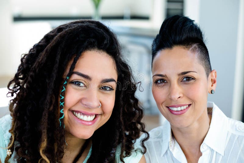 Portrait Of Lesbian Couple Sitting Together On Sofa And