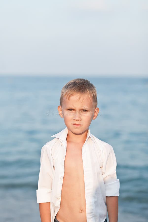 Portrait with little boy standing on the beach with blurry background by the sea