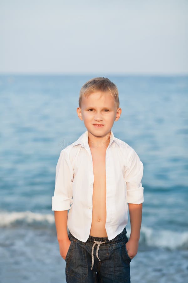 Portrait with little boy standing on the beach with blurry background by the sea