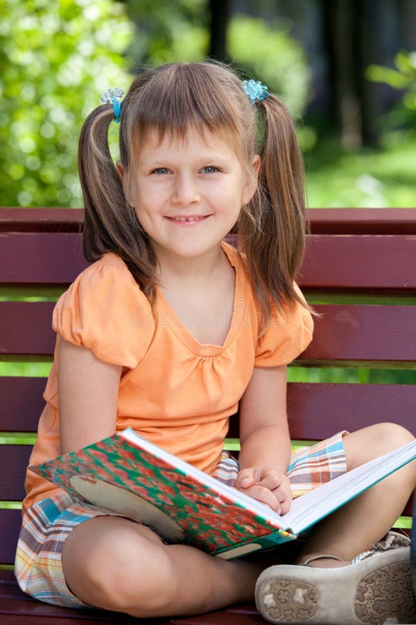 Portrait of little cute smiling girl with book