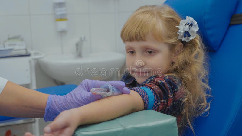 Nurse is taking blood sample from a vein in the arm of little girl royalty free stock photos Nurse is taking blood sample from a vein in the arm of little girl royalty free stock photos