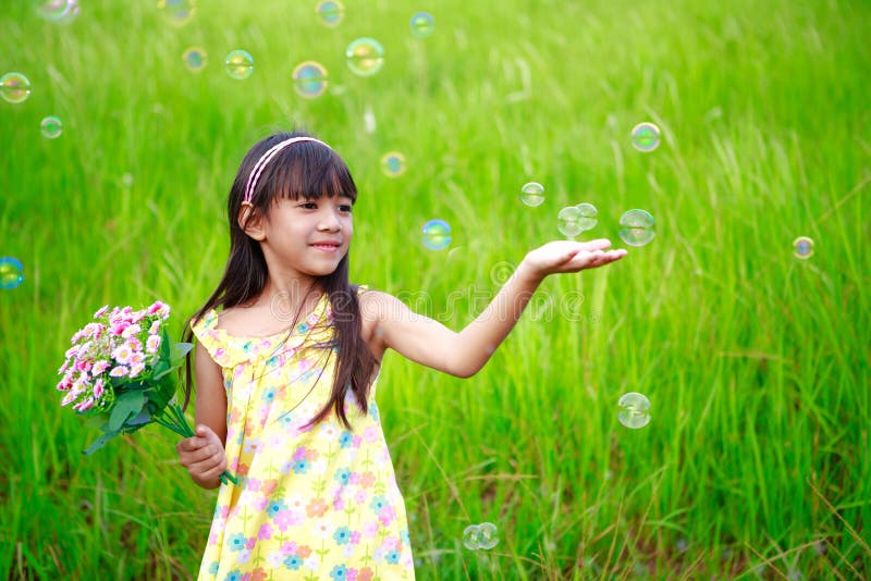 Portrait of little girl enjoy with soap bubbles on green meadow