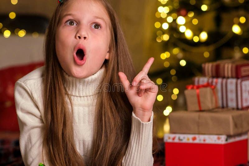 Portrait of little girl on festive Christmas background. Child raised index finger up with great new idea stock image