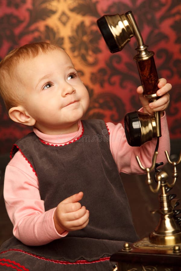 Portrait of little girl holds up retro phone