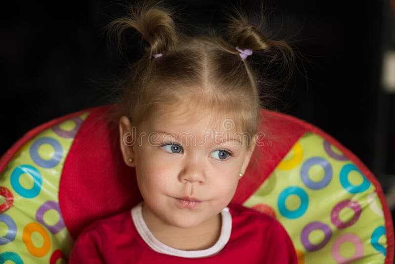 Portrait of little girl with pensive look sitting in feeding chair looking aside royalty free stock photo Portrait of little girl with pensive look sitting in feeding chair looking aside royalty free stock photo