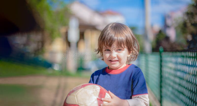 Portrait of little young child boy having fun playing soccer football game on sunny summer day looking at camera holding a dirty royalty free stock images Portrait of little young child boy having fun playing soccer football game on sunny summer day looking at camera holding a dirty royalty free stock images