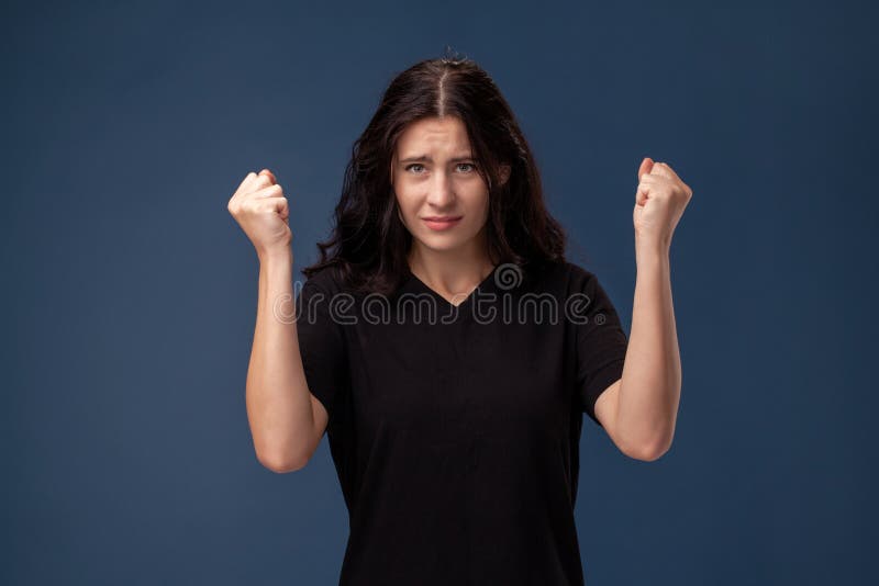 Portrait of a long-haired brunette woman in black t-shirt posing on a gray background and showing different emotions. royalty free stock image Portrait of a long-haired brunette woman in black t-shirt posing on a gray background and showing different emotions. royalty free stock image