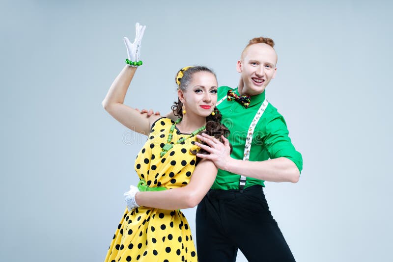 Portrait lovely funny dancer couple dressed in boogie-woogie rock n roll pin up style posing together in studio. Woman in yellow polka dots dress and men in green shirt. Portrait lovely funny dancer couple dressed in boogie-woogie rock n roll pin up style posing together in studio. Woman in yellow polka dots dress and men in green shirt.
