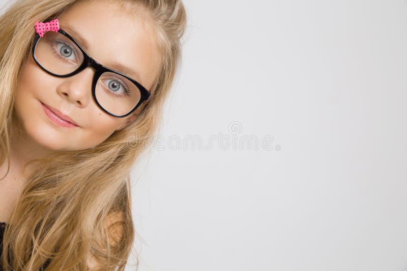 Portrait of a lovely little girl daughter in long blond hair and black glasses with pink bow