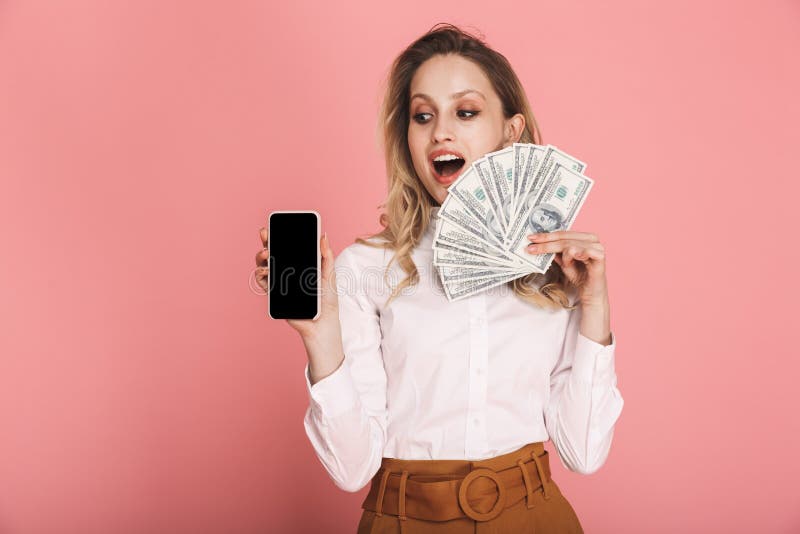 Portrait of lovely woman holding cell phone and money fan isolated over pink background stock image Portrait of lovely woman holding cell phone and money fan isolated over pink background stock image