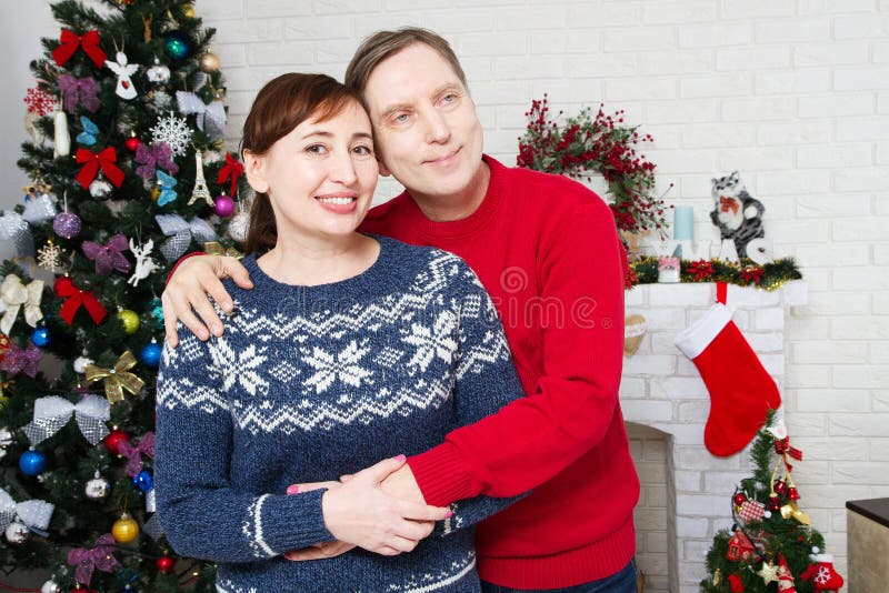 Portrait of loving middle aged couple in living room with christmas tree and decorated fireplace, loving family stock photography Portrait of loving middle aged couple in living room with christmas tree and decorated fireplace, loving family stock photography