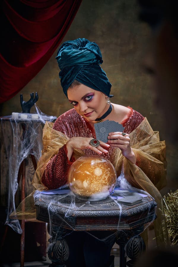 Portrait of magnificent fortune teller woman reading future on magical crystal ball and tarot cards. Concept of vintage