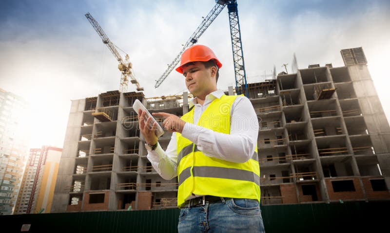 Portrait of male construction engineer standing on building site and using digital tablet stock image