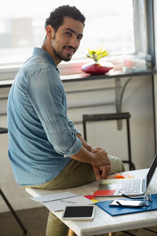 Young man sitting at desk in office and working on computer. Stock